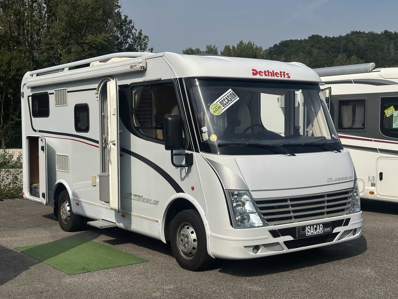 Camping-car Dethleffs blanc stationné sur un parking, porte ouverte