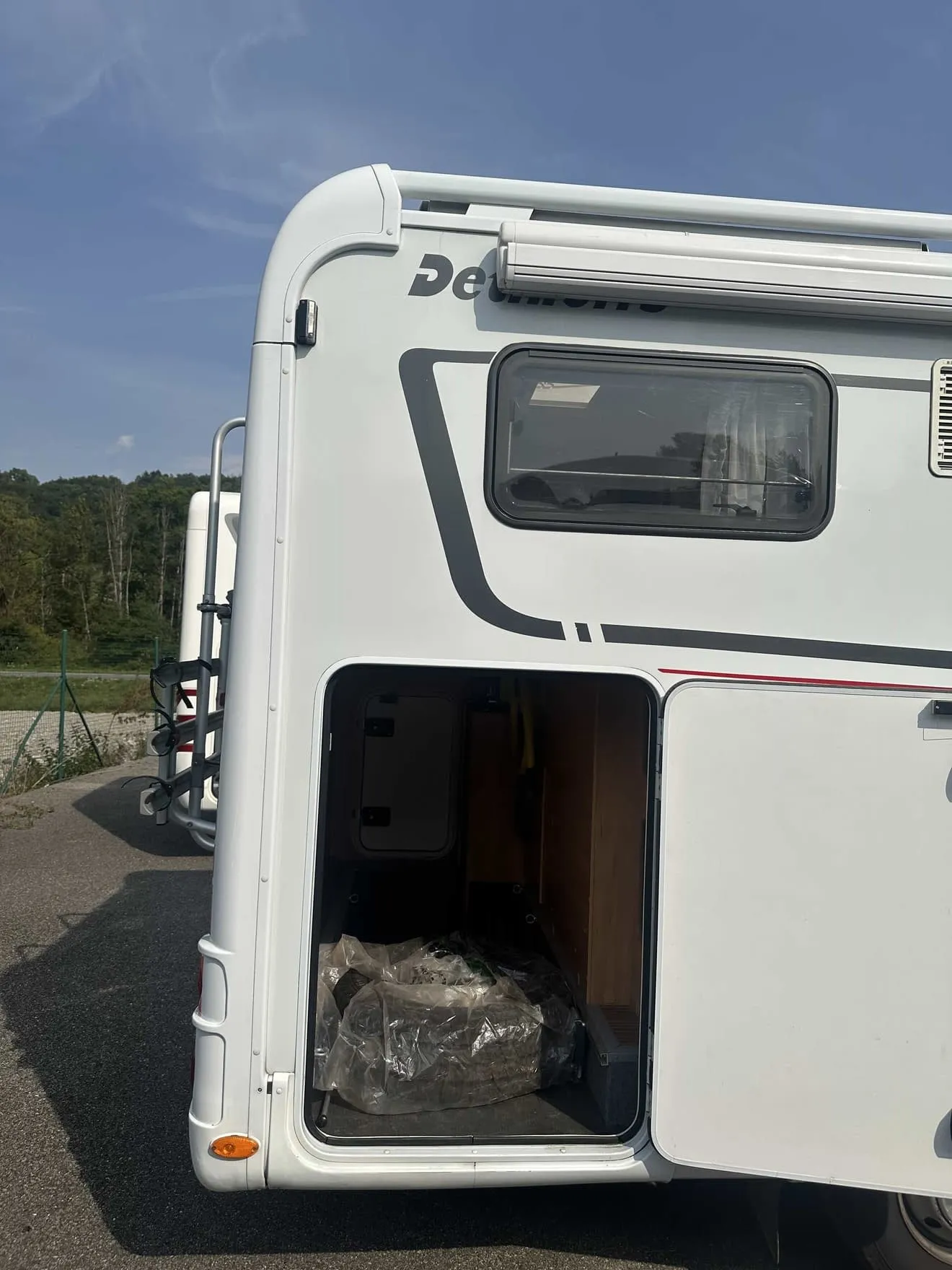 Vue arrière d'un camping-car avec soute ouverte, marque Dethleffs visible