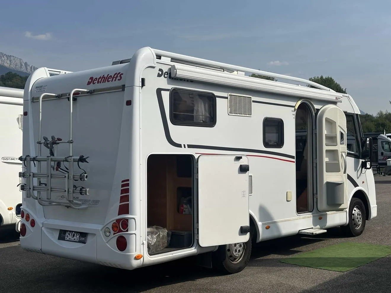 Camping-car Dethleffs stationné avec porte ouverte et porte-vélos à l'arrière.