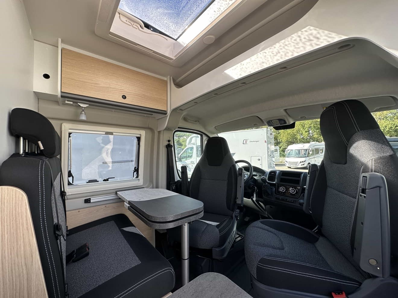 Intérieur d'un camping-car moderne avec sièges et table pliante.