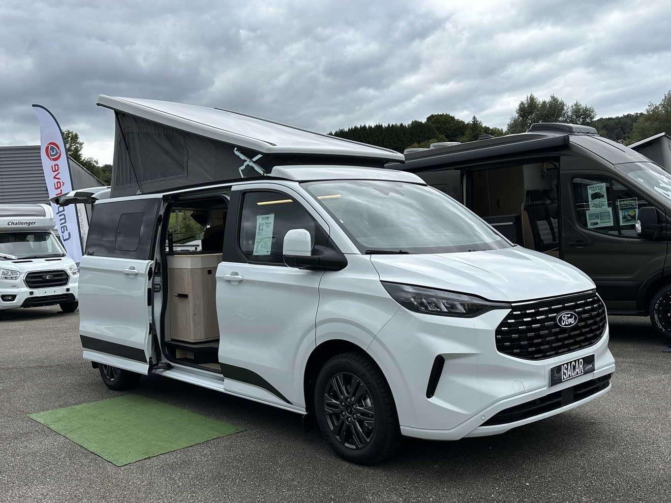 Van aménagé Ford blanc avec toit relevable sur un parking