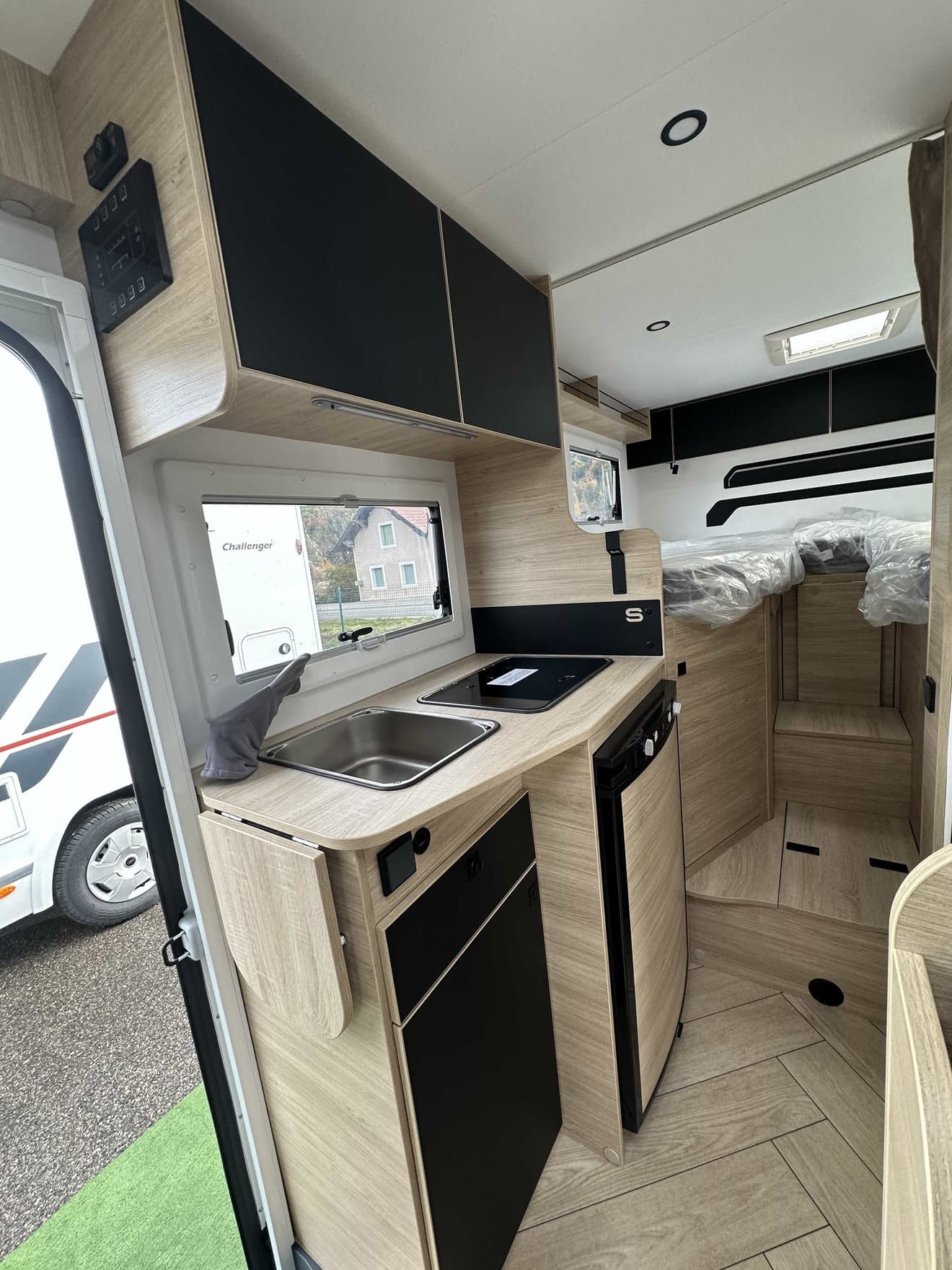 Intérieur moderne d'un camping-car avec cuisine équipée et rangements en bois clair.