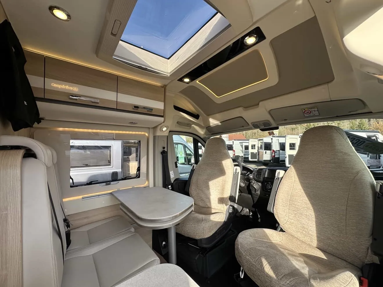Intérieur d'un camping-car moderne avec sièges et table, vue sur le toit ouvrant.