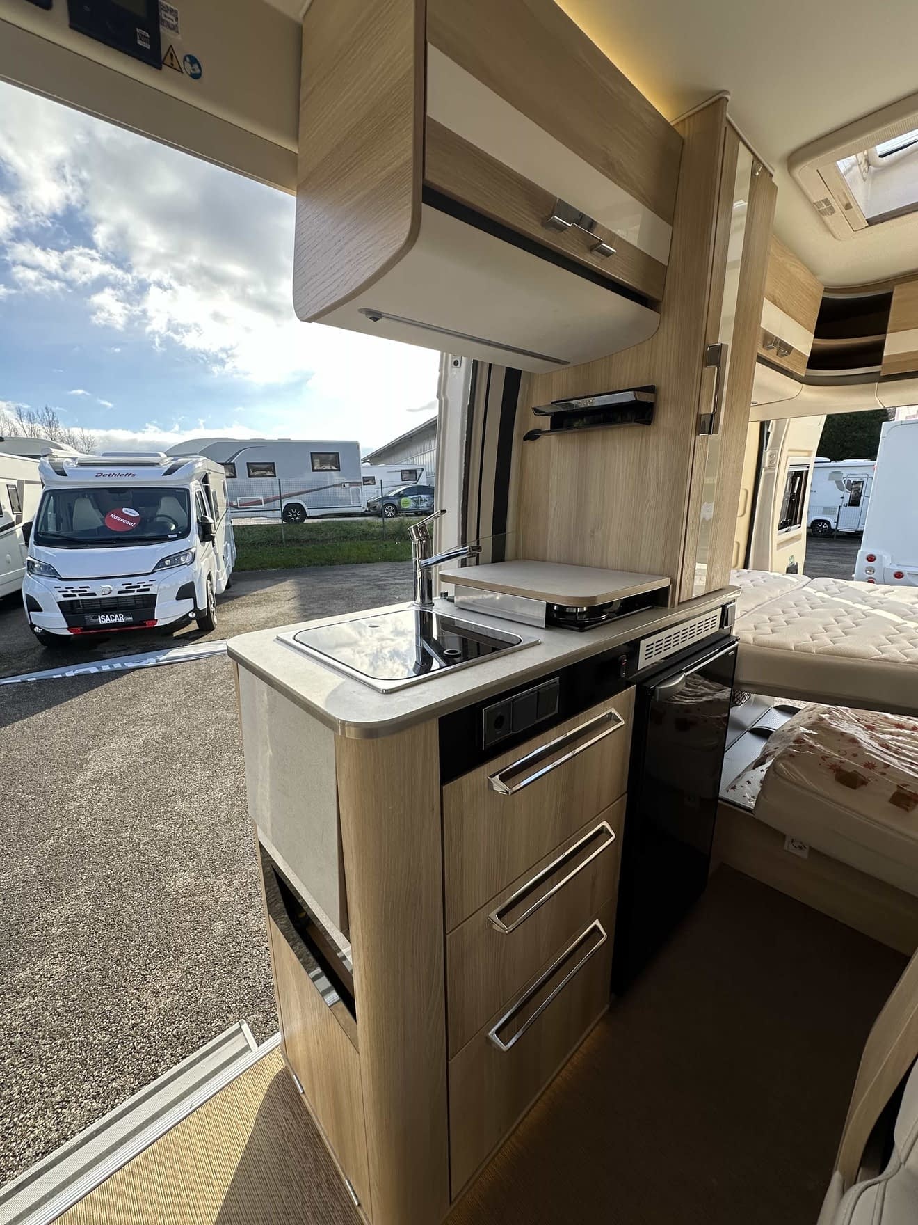 Intérieur d'un camping-car moderne avec cuisine équipée et espace de couchage.