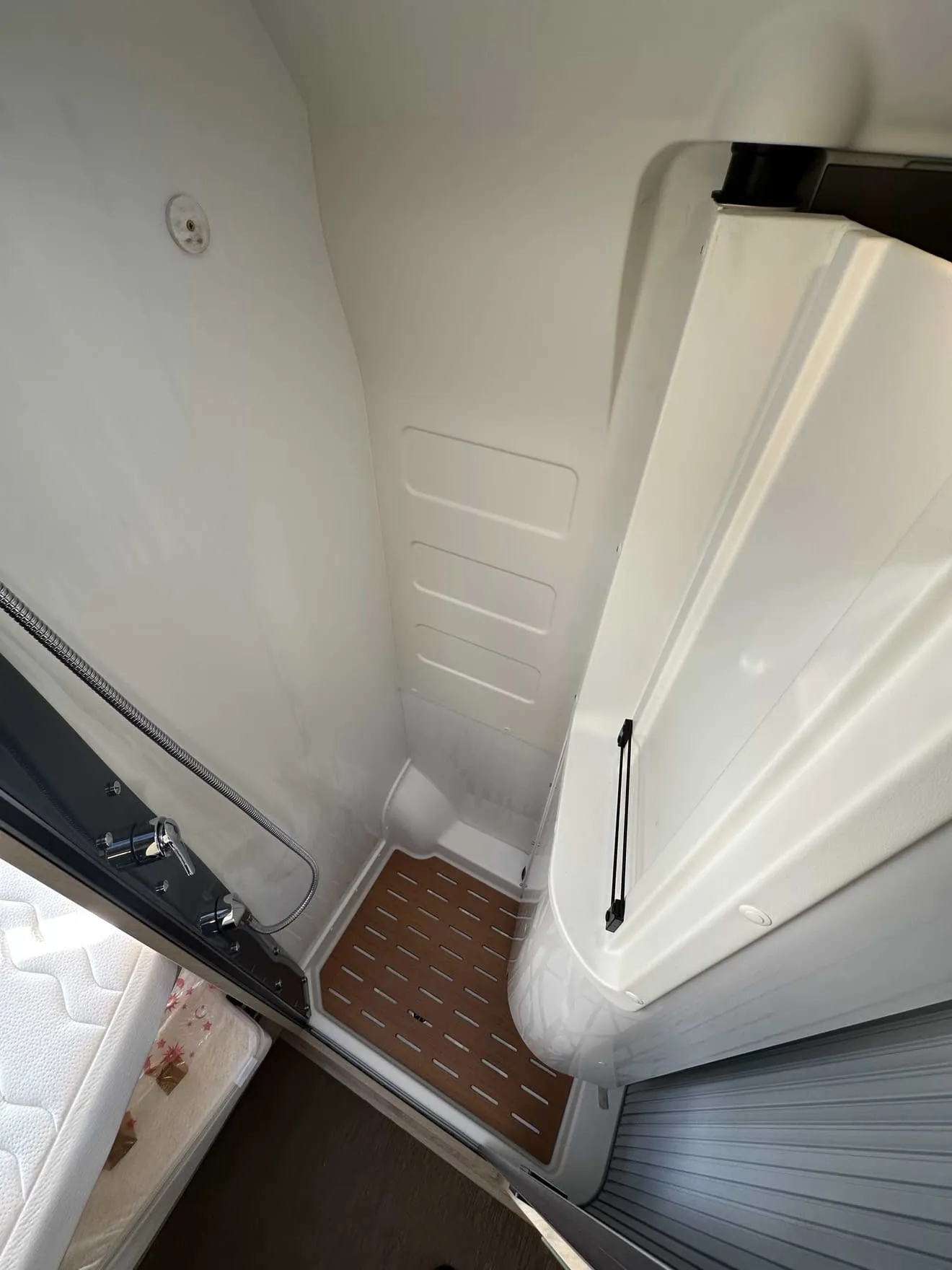 Douche compacte avec sol en bois dans un camping-car moderne.