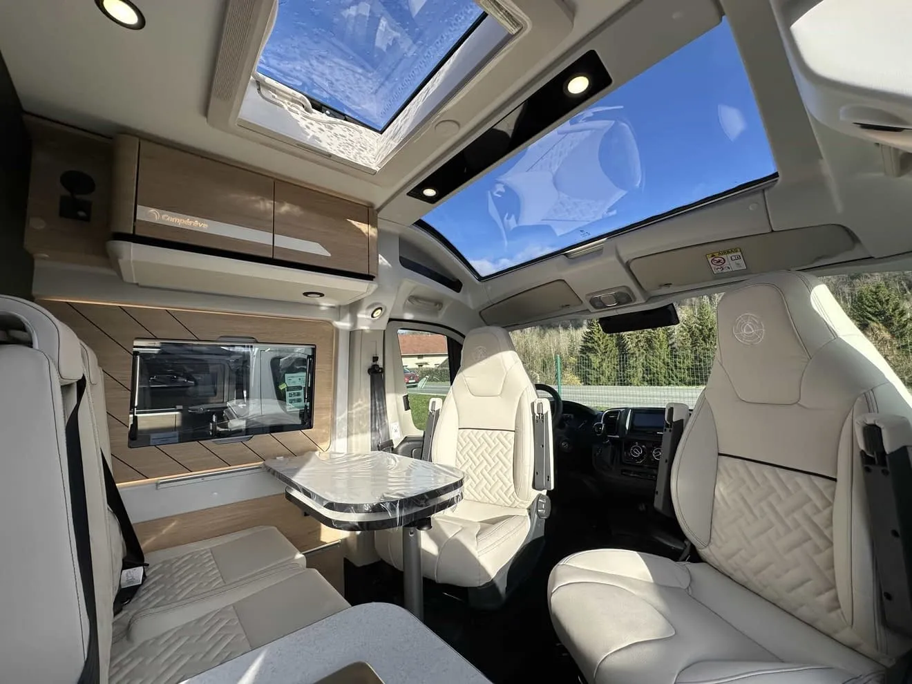 Intérieur d'un camping-car moderne avec sièges en cuir et toit panoramique.
