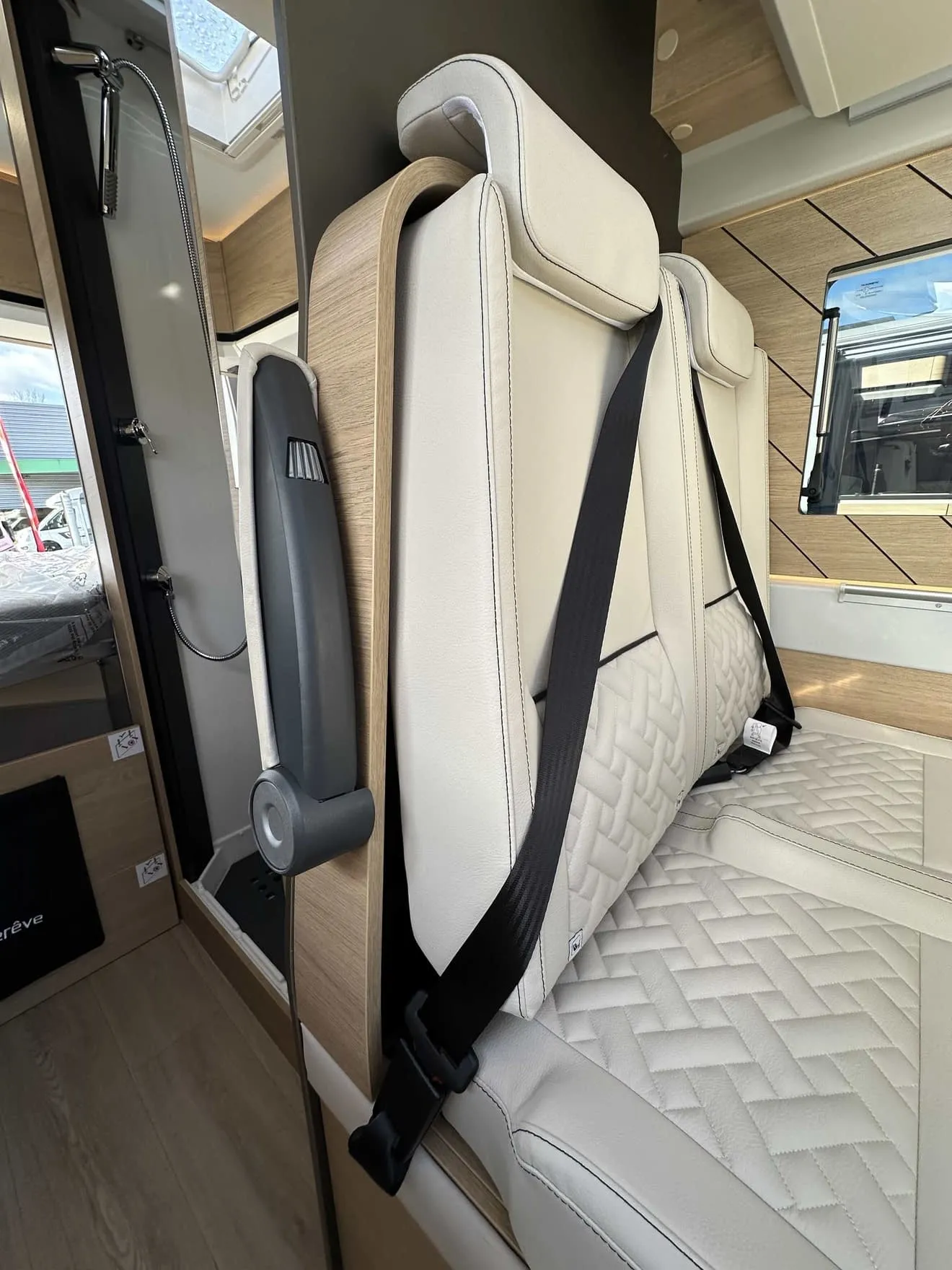 Siège de camping-car avec ceinture de sécurité et revêtement en cuir beige.
