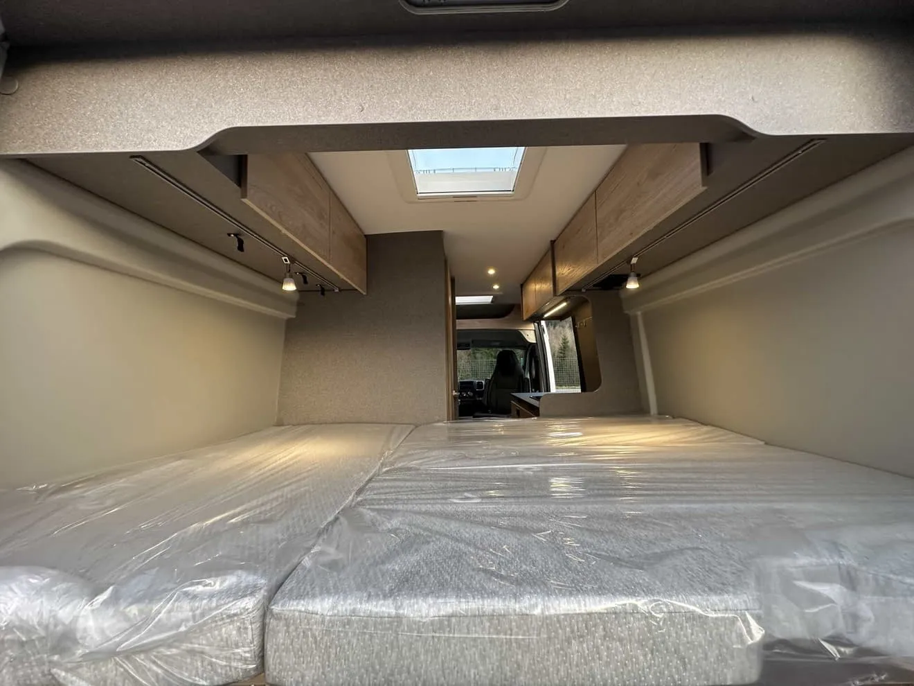 Intérieur d'un van aménagé avec lit double et rangements en bois clair