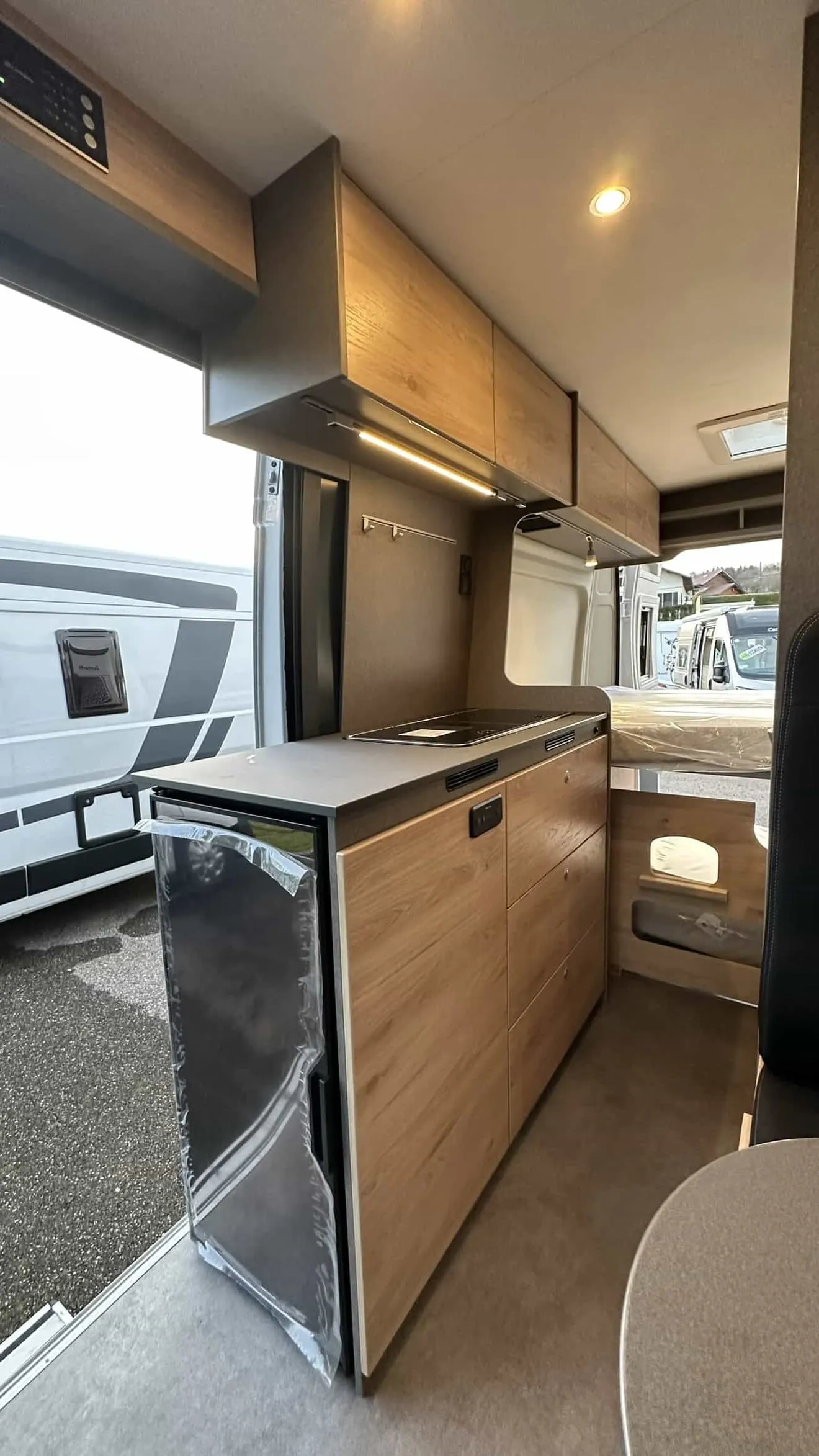 Intérieur d'un van aménagé avec cuisine moderne et rangements en bois clair.