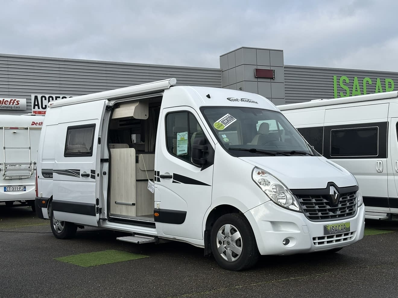 Camping-car Renault blanc stationné devant un concessionnaire